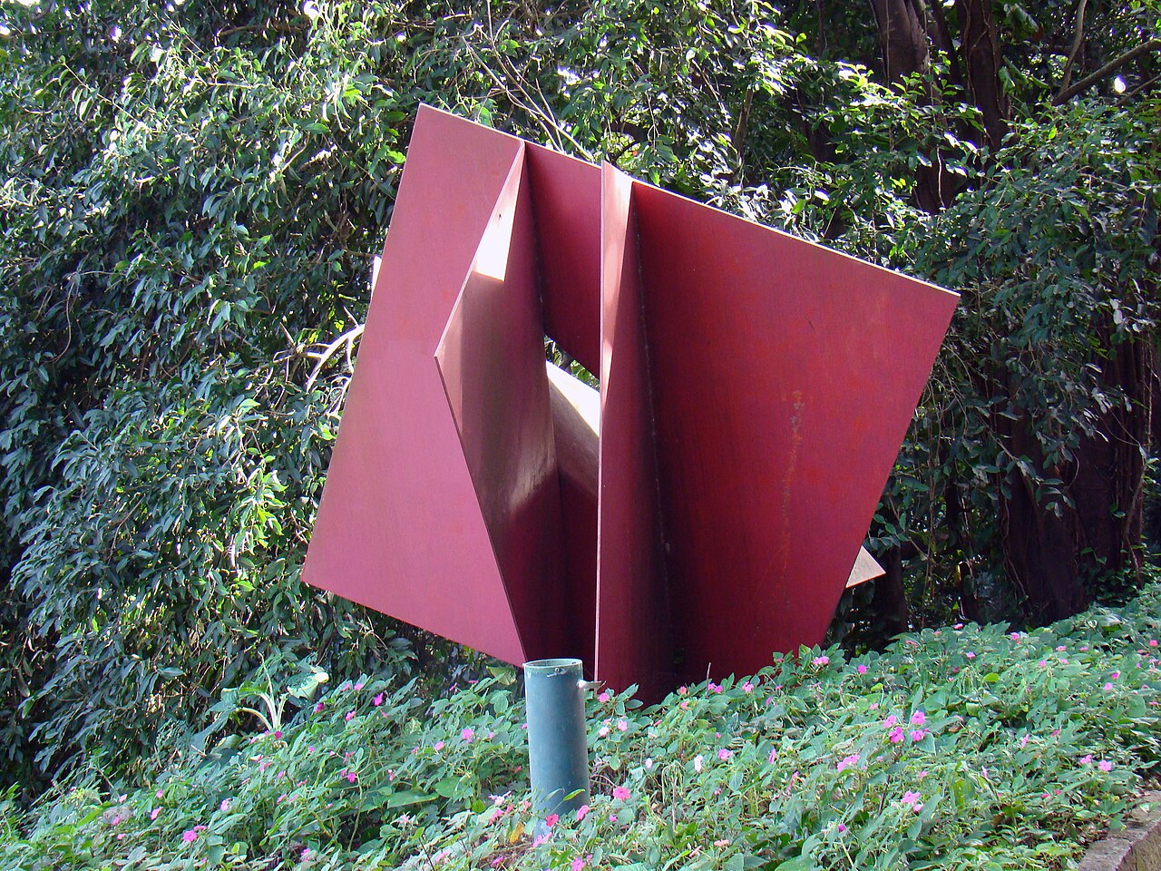A geometric outdoor sculpture by Franz Weissmann surrounded by greenery in Parque da Catacumba
