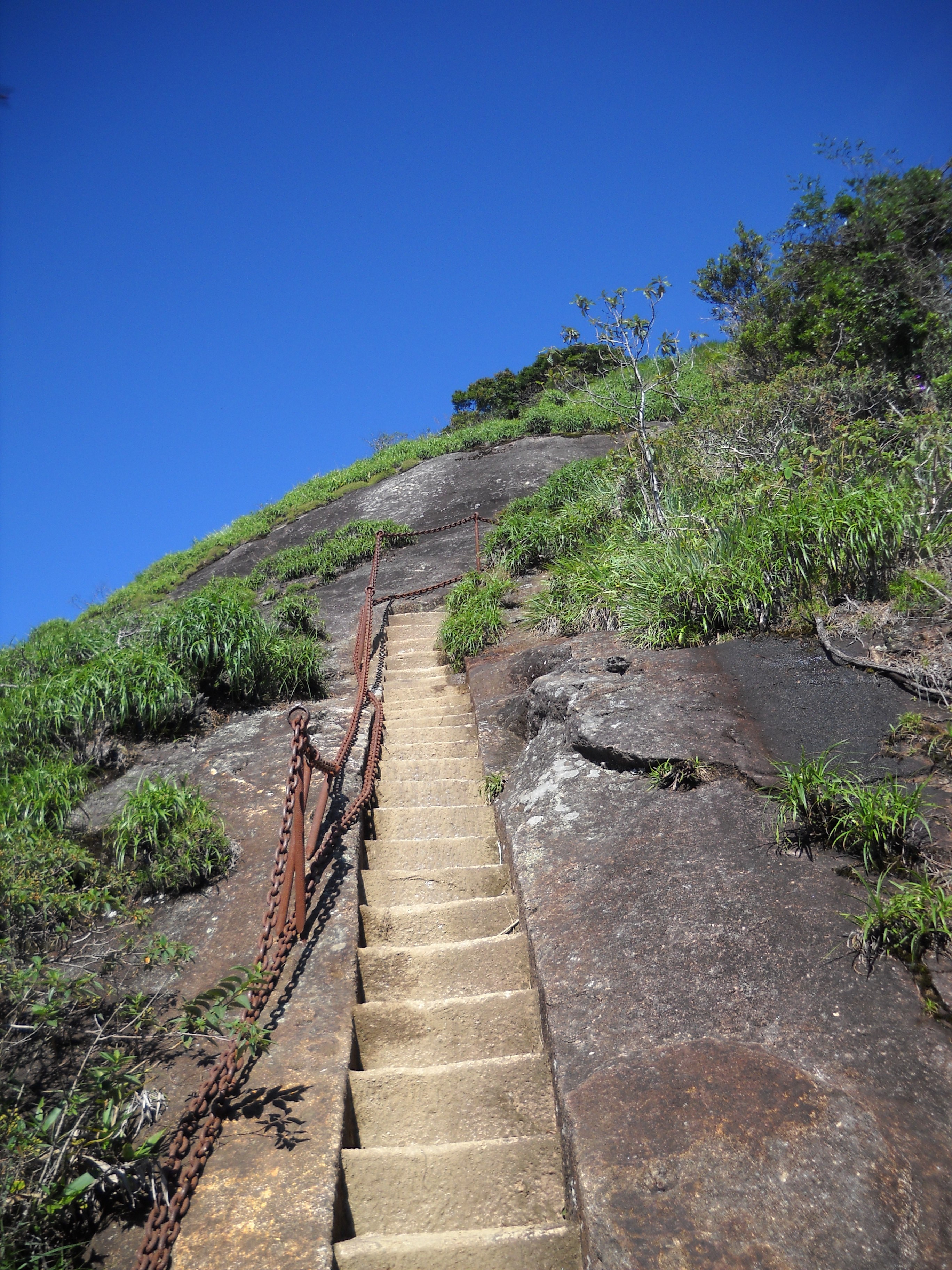 Stone steps and fixed chain handrails on the exposed final ascent to Pico da Tijuca’s summit